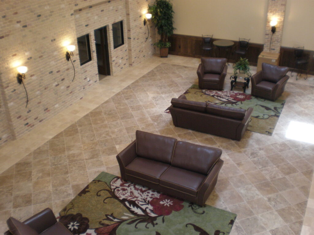 A lobby with couches, chairs and rugs.