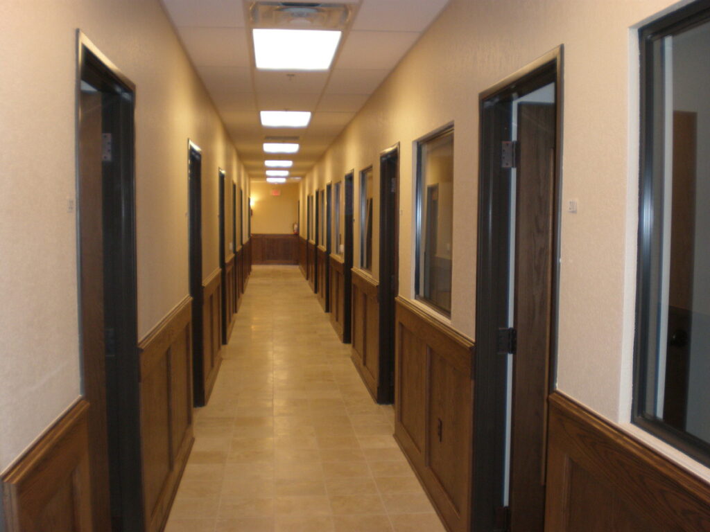 A long hallway with many doors and windows.
